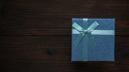 Sparkling Blue Gift Box with Ribbon on Dark Wooden Backgroundの写真素材