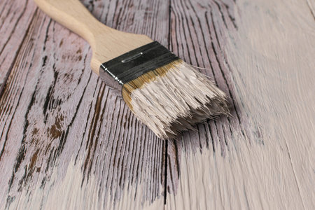 Painting Brush on Wooden Surface with Fresh White Paint Close-Upの写真素材
