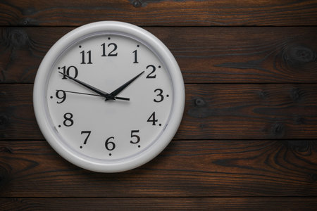 Simple White Wall Clock on Dark Wooden Background Showing Timeの写真素材