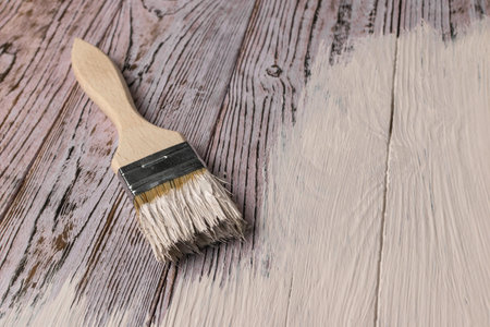 Wood Painting Process with Brush and White Paint on Rustic Wooden Surfaceの写真素材