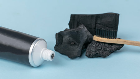 Charcoal Toothpaste Tube with Bamboo Toothbrush and Charcoal Pieces on Light Backgroundの写真素材