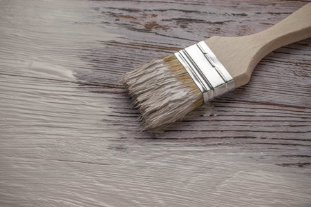 Close-Up of Paintbrush Applying White Paint on Wooden Surface for DIY Home Improvementの写真素材