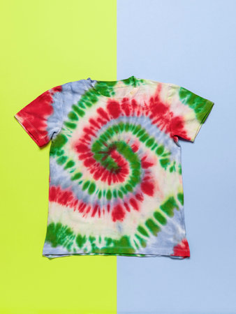 Colorful Tie-Dye T-Shirt on Split Yellow and Blue Background for Creative Apparel Conceptsの写真素材