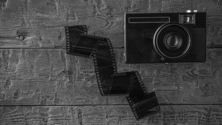 Vintage Camera with Film Roll on Rustic Wooden Background in Black and Whiteの写真素材