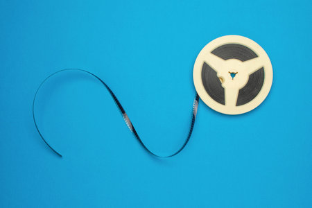 Vintage Film Reel on Blue Background - Symbol of Retro Cinema and Analog Technologyの写真素材