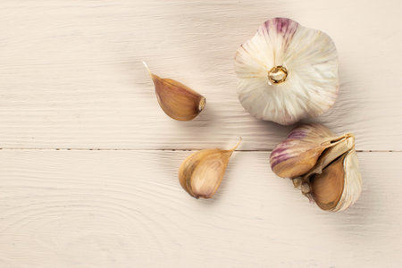 Fresh Garlic Cloves and Bulb on Light Wooden Surface: Culinary Spice and Healthy Ingredientの写真素材