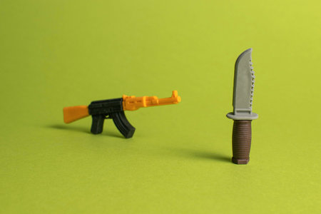 Toy Weapons Concept: Brightly Colored Plastic Gun and Knife on Green Backgroundの写真素材
