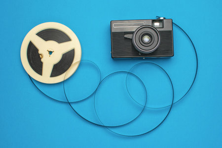 Retro Camera and Film Reel on Blue Background: Vintage Photography Theme