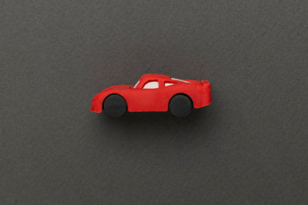Minimalist Red Toy Car on Dark Green Background in Artistic Compositionの写真素材