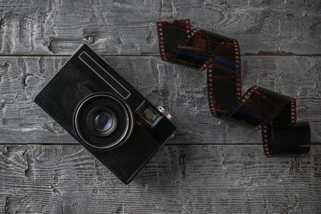 Vintage Camera and Film Roll on Rustic Wooden Background Reflecting Nostalgic Photography Trendsの写真素材