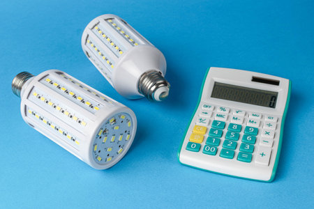 Energy-Efficient LED Light Bulbs and Calculator on Blue Background for Budgetingの写真素材
