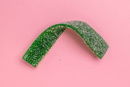 Sugar-Coated Green Candy Belt on Pink Background: Sweet and Vibrant Stock Photo