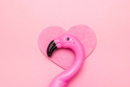 Pink Flamingo Toy with Heart on Soft Pink Background - Trendy Minimalist Stock Photoの写真素材