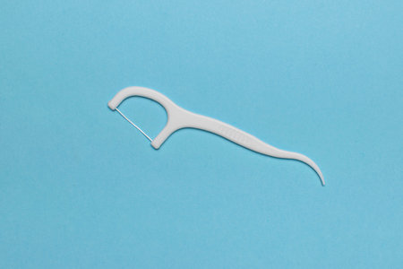 White Dental Floss Pick on Blue Background: Oral Hygiene and Dental Care Stock Imageの写真素材