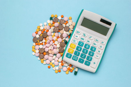 Healthcare Costs Concept: Calculator with Colorful Pills on Light Blue Backgroundの写真素材