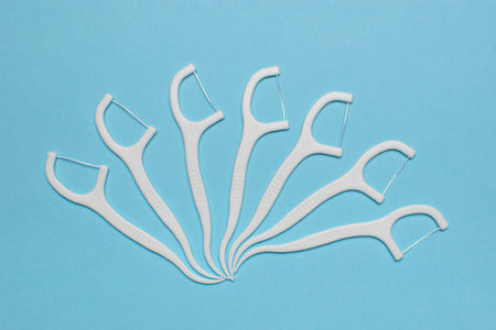 White Dental Floss Picks Arranged in a Fan Shape on Light Blue Backgroundの写真素材