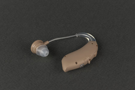 Modern Beige Hearing Aid Device on Dark Background for Hearing Assistanceの写真素材