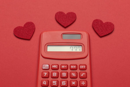 Red Calculator with Heart Symbols on Red Background - Love and Finance Conceptの写真素材
