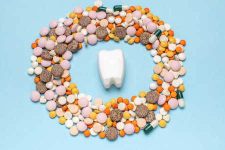 Tooth Surrounded by Colorful Pills on Blue Background - Healthcare and Dental Conceptsの写真素材