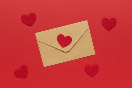 Valentine's Day Brown Envelope with Red Heart Decorations on Red Backgroundの写真素材