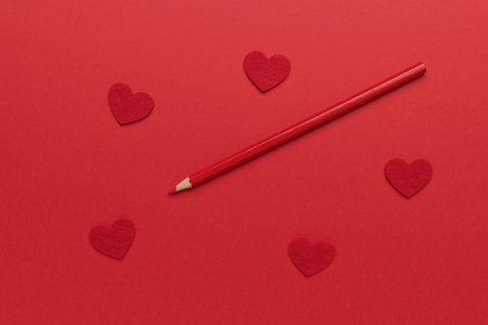 Red Pencil on Vibrant Red Background with Heart Shapes - Symbol of Love and Creativity