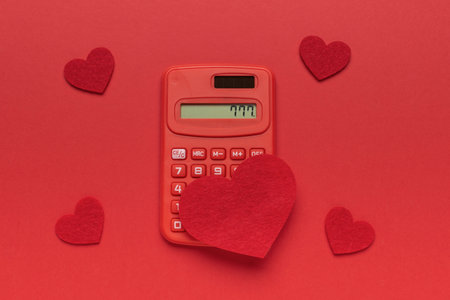 Red Calculator Displaying 777 Surrounded by Felt Hearts on Red Backgroundの写真素材