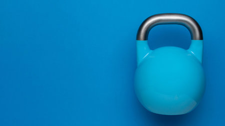 Bright Blue Kettlebell on Minimalistic Blue Background for Fitness and Home Gym Conceptsの写真素材