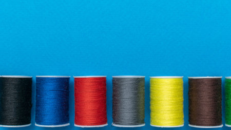 Colorful Thread Spools on Blue Background: Vibrant Textile Essentials for Sewing and Crafting