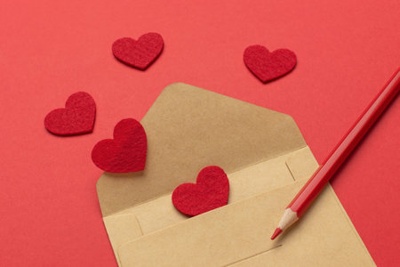 Romantic Valentine's Envelope with Red Hearts and Pencil on Red Backgroundの写真素材