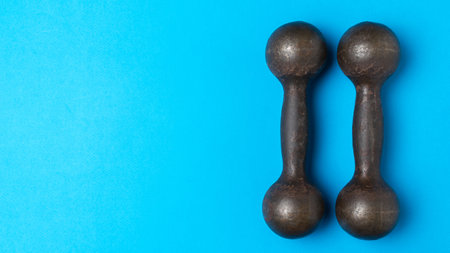 Vintage Dumbbells on Vibrant Blue Background: Fitness and Nostalgia Combined in a Retro Aestheticの写真素材