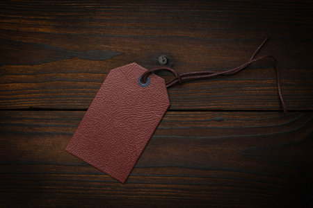 Brown Leather Tag on Rustic Wooden Surface with Textured Backgroundの写真素材