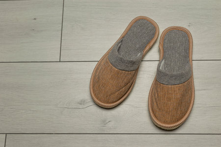 Cozy Brown Slippers on Wooden Floor - Comfy Indoor Footwear for Relaxed Home Daysの写真素材