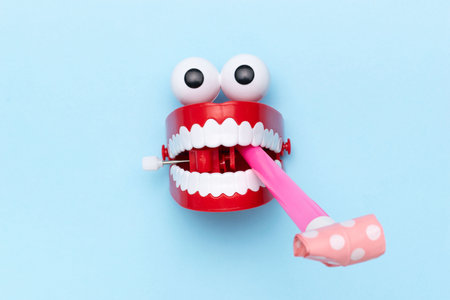 Whimsical Wind-Up Teeth Toy with Googly Eyes and Party Blowout on Blue Backgroundの写真素材