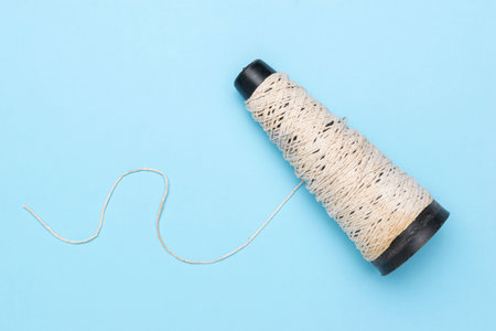 Minimalist Spool of Twine Against Blue Background: Craft, DIY, and Textile Trends