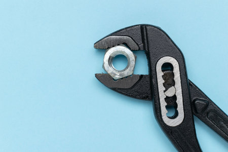 Adjustable Wrench Gripping Nut on Blue Background: Industrial and DIY Tool Conceptの写真素材