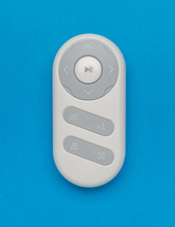 Modern Remote Control on Blue Background: Minimalist Device for Multimedia and Ergonomic Interactionの写真素材