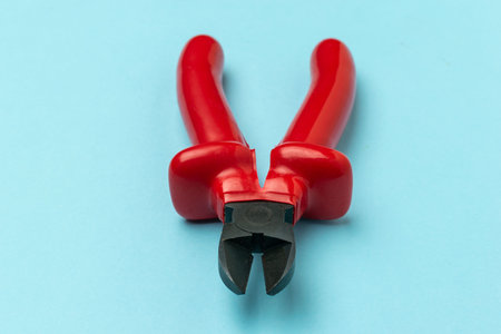 Red Wire Cutter Isolated on Blue Background Highlighting Tool Design and Functionalityの写真素材