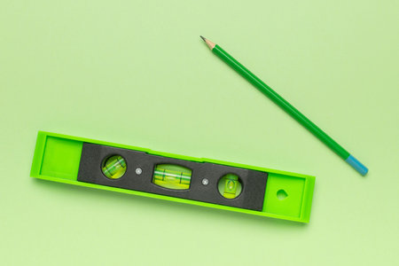 Green Level Tool and Pencil on Green Background: Precision and Alignment in Minimalist Styleの写真素材