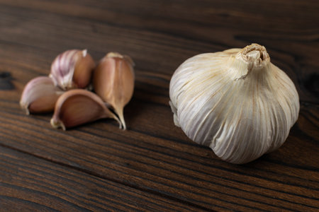 Fresh Garlic Cloves and Whole Bulb on Rustic Wooden Surfaceの写真素材