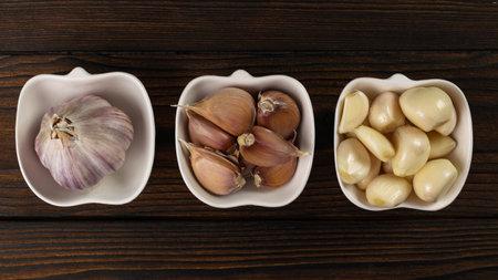 Fresh Garlic: Whole Bulbs, Cloves, and Peeled Varieties Displayed on Rustic Wooden Surfaceの写真素材