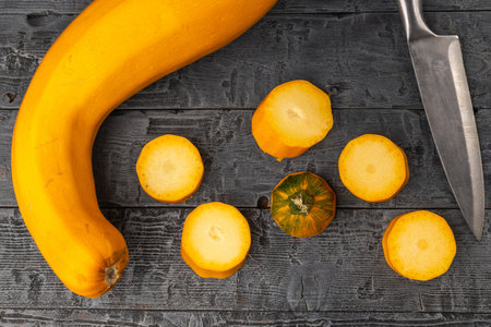 Sliced Yellow Zucchini on Rustic Wood Surface with Knifeの写真素材