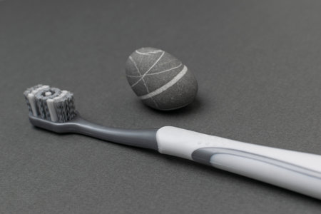 Modern Toothbrush and Zen Stone on Minimalist Gray Background