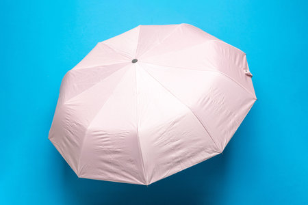 Pink Umbrella on Vibrant Blue Background: Minimalist Weather Conceptの写真素材