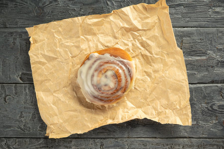 Freshly Iced Cinnamon Roll on Rustic Parchment Paper Backgroundの写真素材