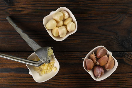 Fresh Garlic Cloves with Press on Rustic Wooden Table - Culinary Preparation and Ingredient Conceptの写真素材