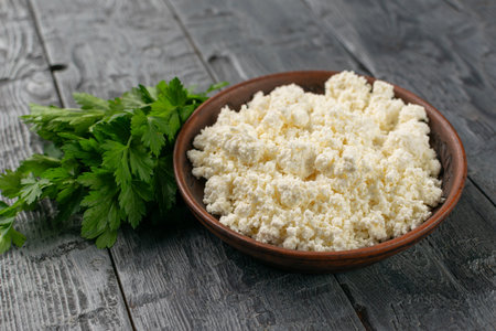 Fresh Cottage Cheese in Rustic Bowl with Parsley on Wooden Table - Healthy Vegetarian Food Conceptの写真素材