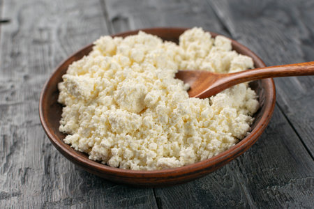 Fresh Organic Cottage Cheese in Rustic Wooden Bowl on Gray Wooden Table for Healthy Eatingの写真素材