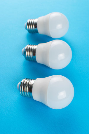 Three LED Light Bulbs on Vibrant Blue Background for Modern Energy Conceptの写真素材
