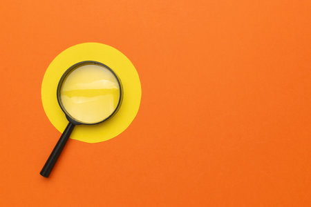 Magnifying Glass on Orange and Yellow Minimalist Background for Exploration and Discovery Conceptsの写真素材