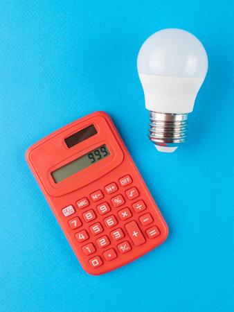 Red Calculator and Light Bulb on Blue Background: Innovative Ideas and Financial Calculationsの写真素材